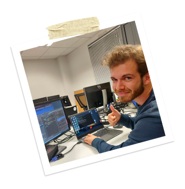 Jeune développeur travaillant sur plusieurs écrans avec du code visible, souriant à la caméra, dans un environnement de formation Java