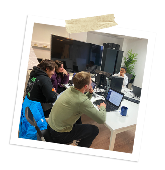 Équipe de stagiaires travaillant ensemble sur des ordinateurs dans un bureau, illustrant l'entraide et la collaboration chez Oxyl