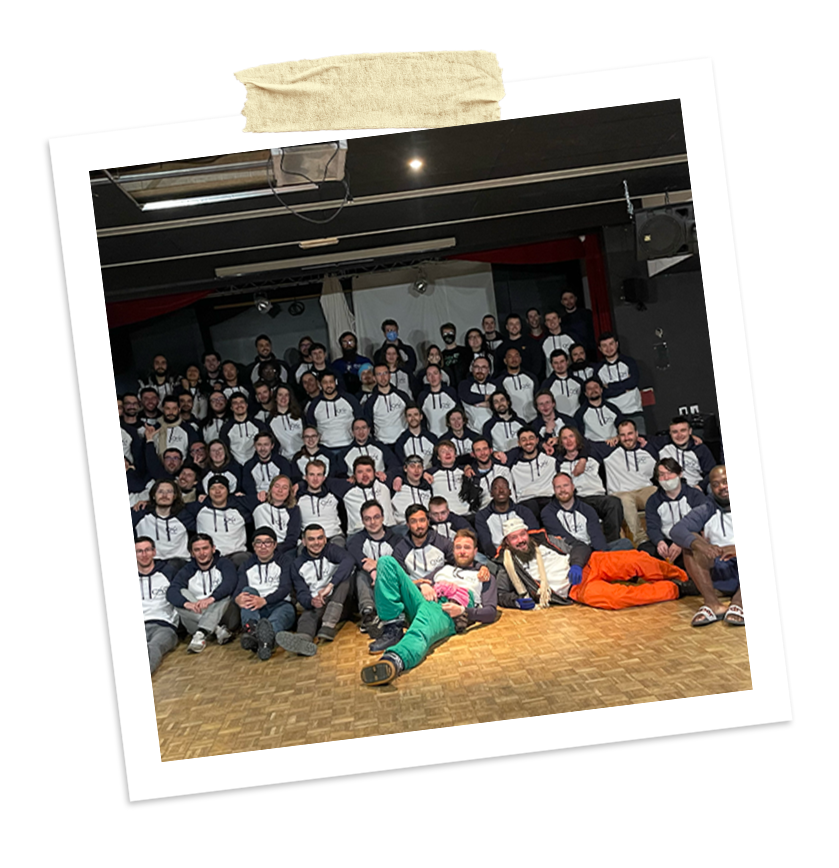 Photo de groupe d'ingénieurs en tenue décontractée sweat à capuche gris et blanc, lors d'un séminaire d'été, posant ensemble dans une salle lors d’un séminaire hiver