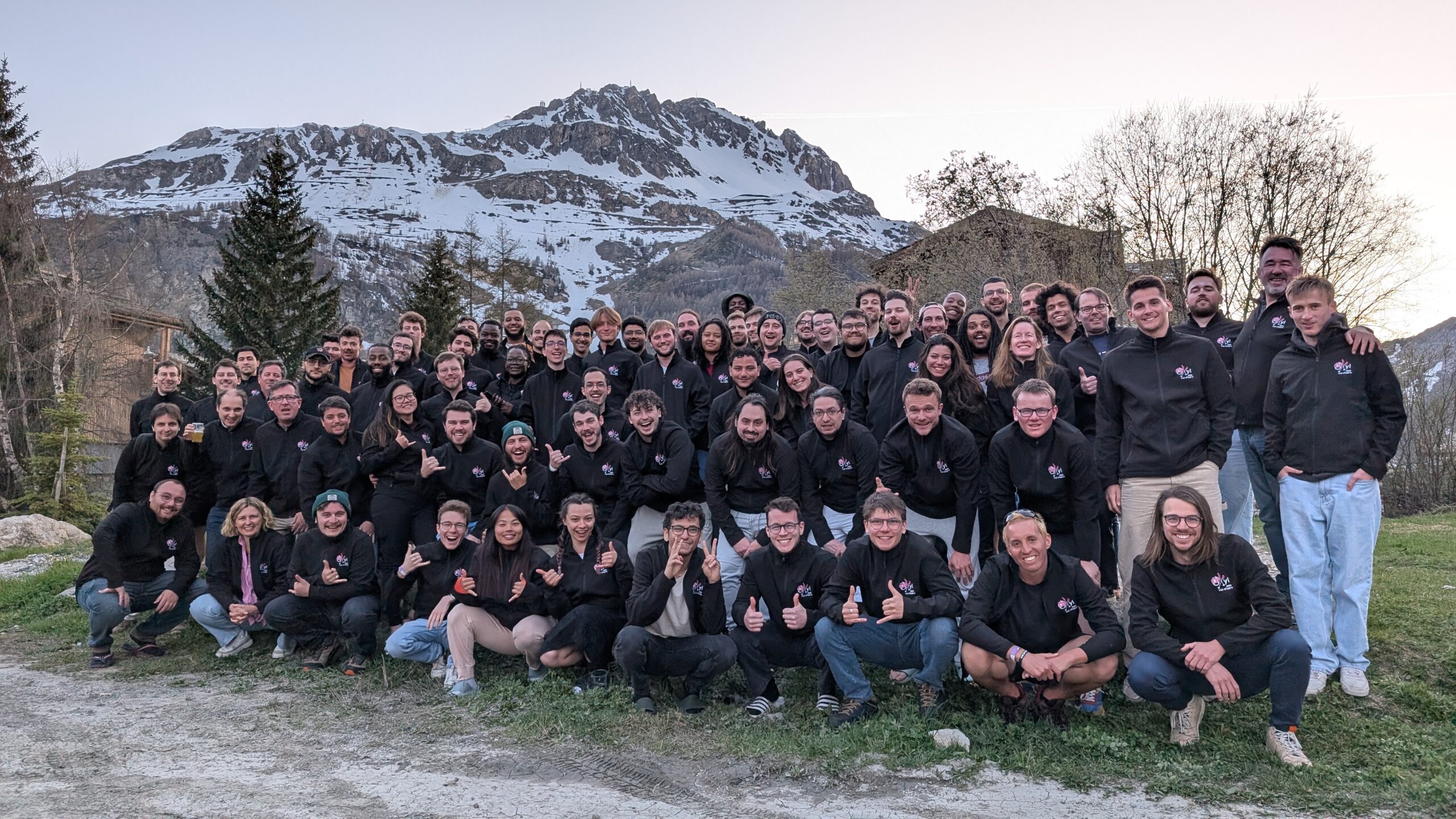 Photo de groupe des développeurs d'Oxyl lors d'un team building à la montagne, avec un paysage enneigé en arrière-plan. L'équipe porte des vestes noires assorties avec le logo Oxyl et pose dans une ambiance conviviale et décontractée.