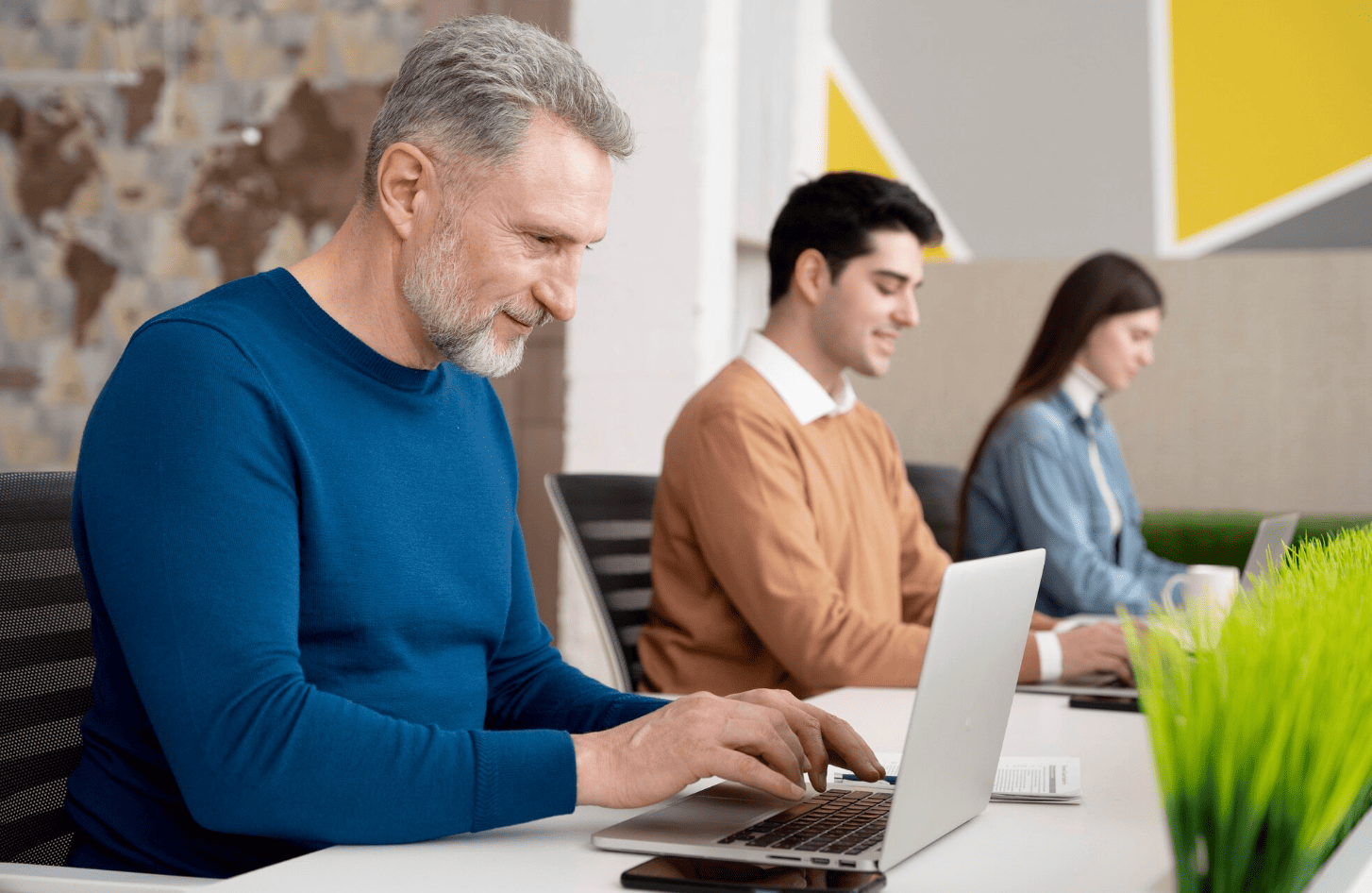 Professionnels suivant une formation à l’automatisation et aux outils d’IA sur ordinateur portable dans un environnement de travail collaboratif.