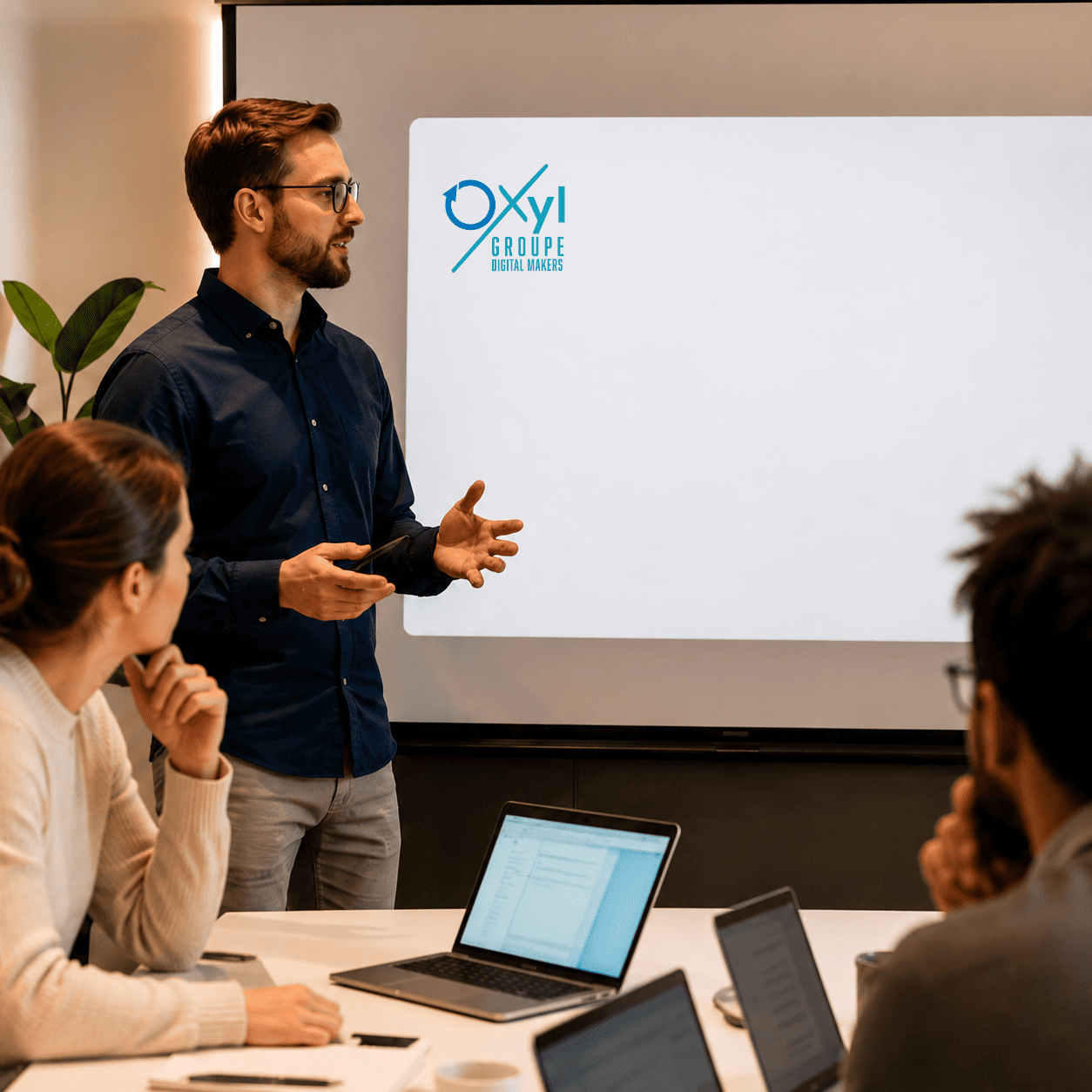 Formation professionnelle chez Oxyl : un formateur présente un support de cours devant plusieurs participants réunis en salle de réunion.